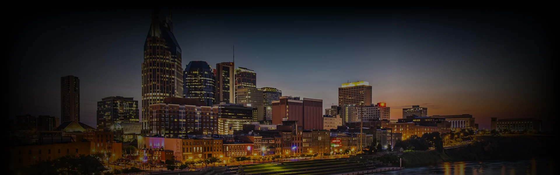 Skyline at dusk showcasing downtown Nashville's iconic high-rises with warm city lights, a perfect backdrop for Atlanta to Nashville Car Service promotions.